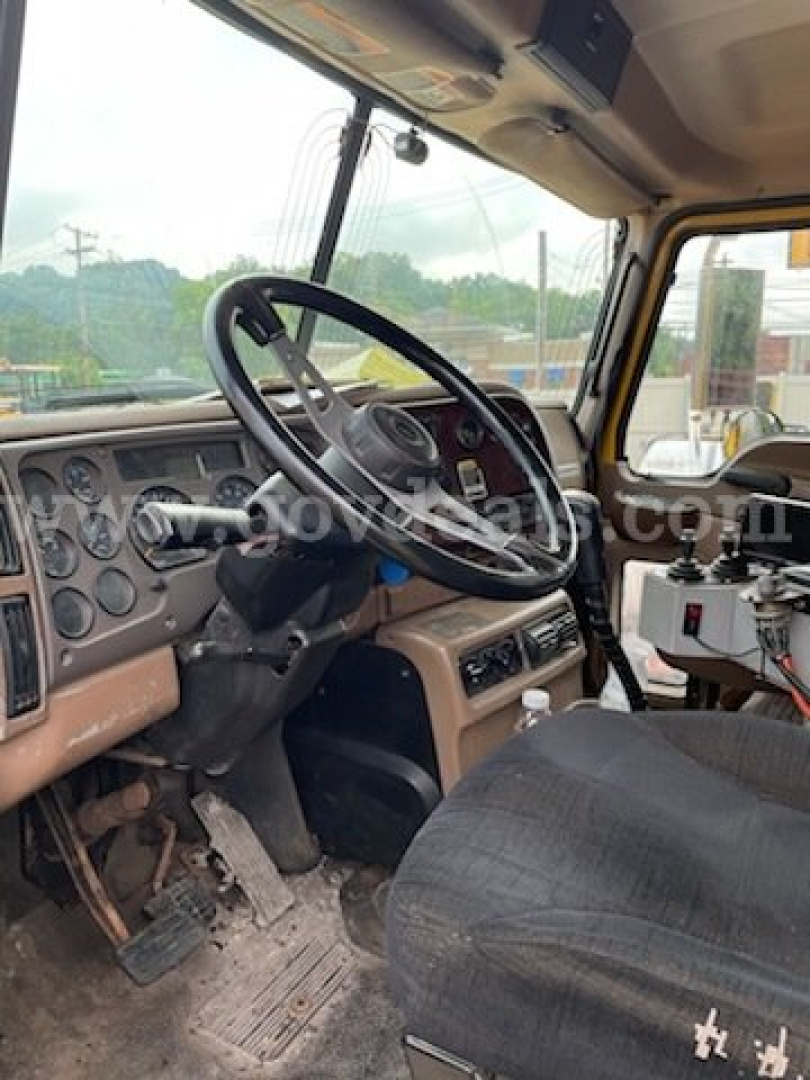 Cab interior of a 2006 Mack CV713 dump truck showing steering wheel and dashboard with visible pedals and driver seat.