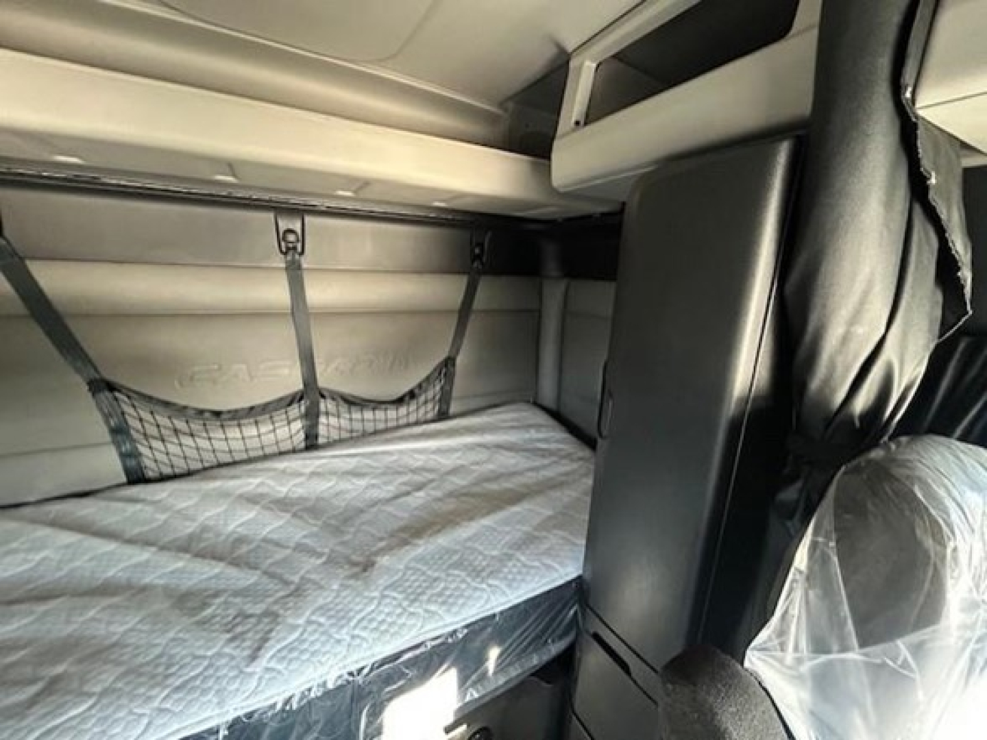 Interior sleeper cab bunk area of a used 2022 Freightliner Cascadia 116 showing a single bunk with mattress and net storage, front seat and partition visible.