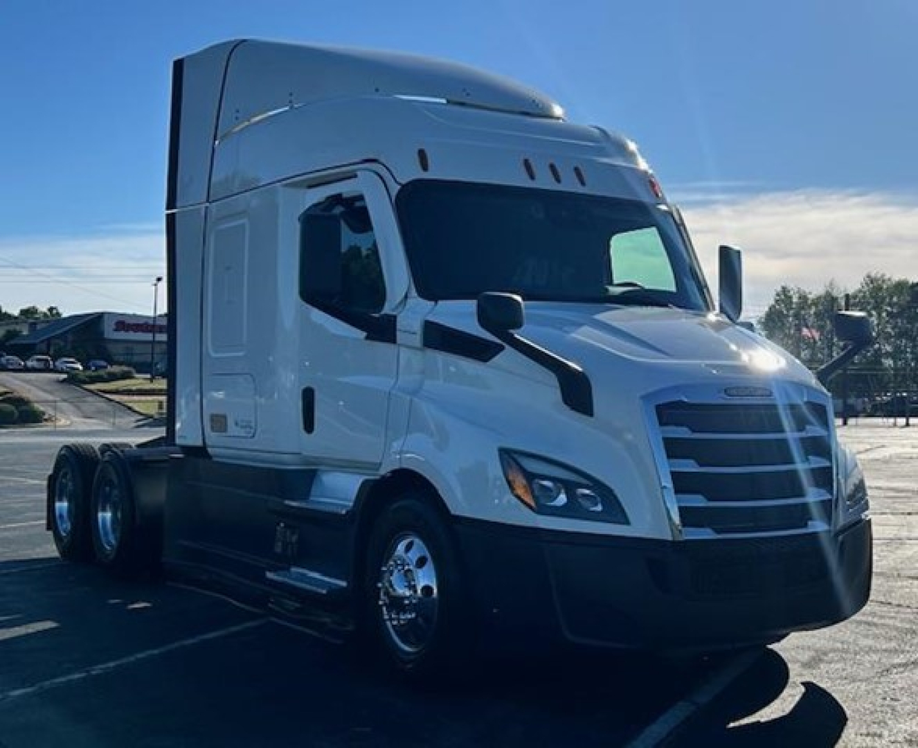 Freightliner Cascadia 116 sleeper cab truck front-left view with white cab and black bumper.