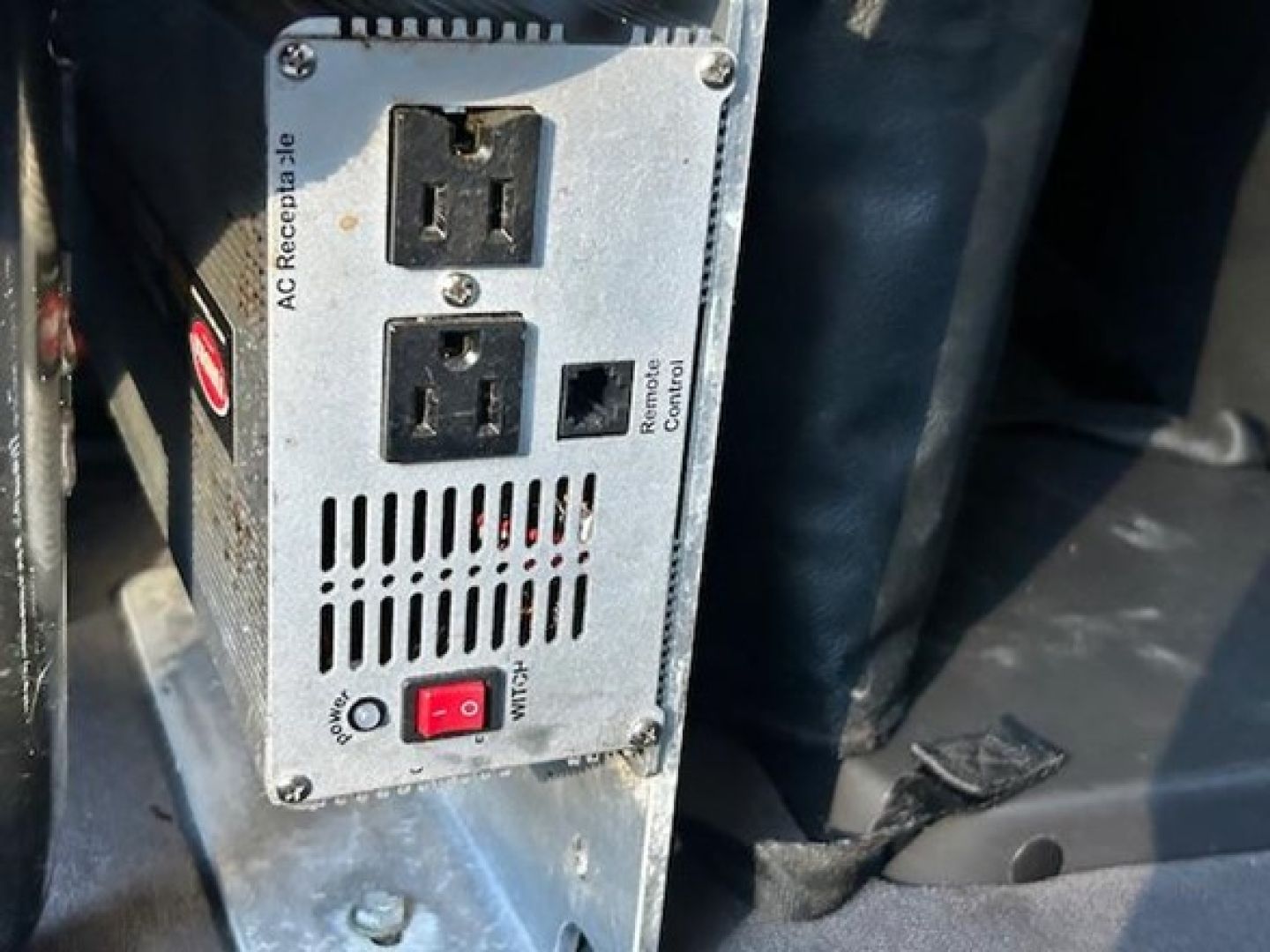 Freightliner Cascadia engine bay showing power inverter and AC receptacle panel with two outlets and switch.