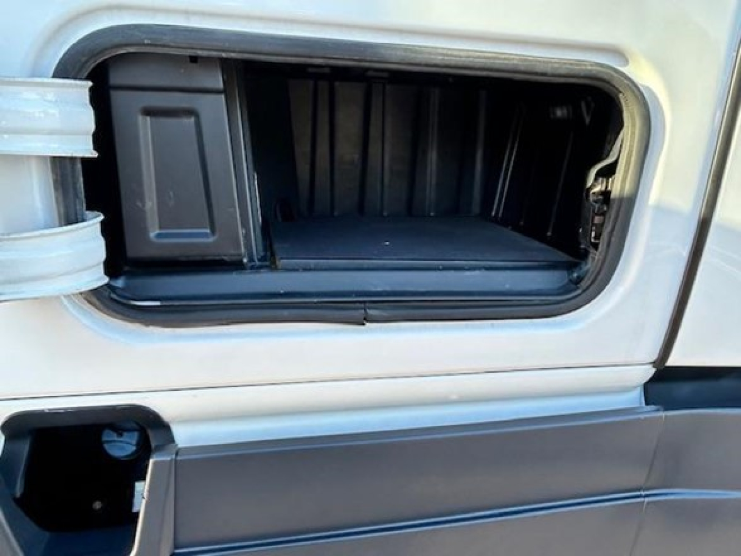 Truck exterior showing front storage compartment empty hatch in midsection of Freightliner Cascadia cab.