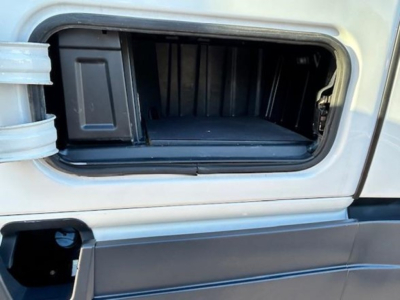 Truck exterior showing front storage compartment empty hatch in midsection of Freightliner Cascadia cab.