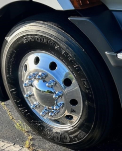 Freightliner Cascadia wheel and tire close-up showing Goodyear Endurance tire and polished chrome hubcap on front axle.