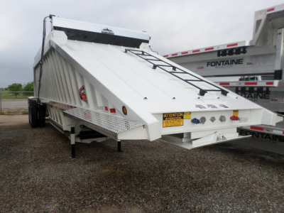 Dump trailer with folded tailgate and ladder rack showing 'ATTENTION' warning sticker and control panels; white exterior with Diamond plate step; Fontaines in background.