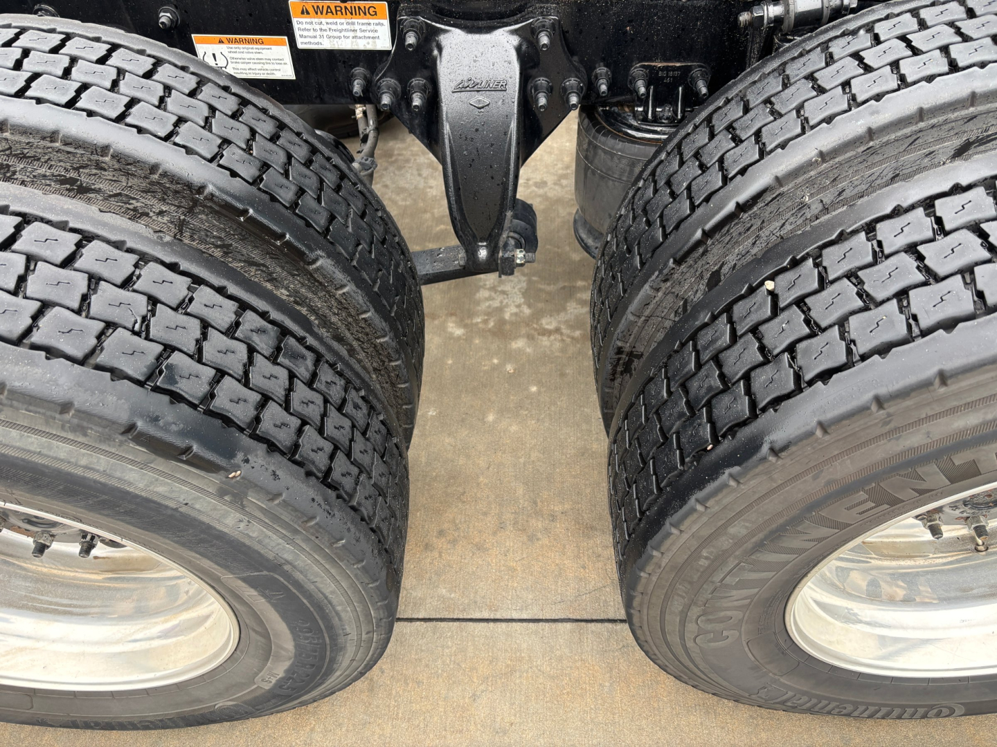 Freightliner PT126064ST chassis showing dual rear axles with tires and suspension, center differential housing visible under cab area.
