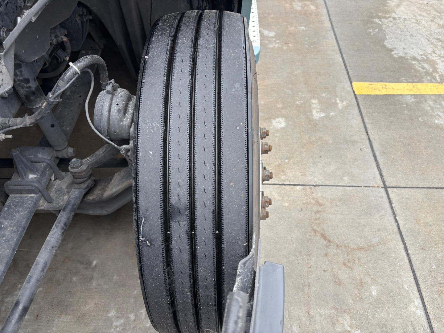 Conventional sleeper truck front wheel with multiple tread grooves and wheel hub bolts visible, part of Freightliner PT126064ST chassis.