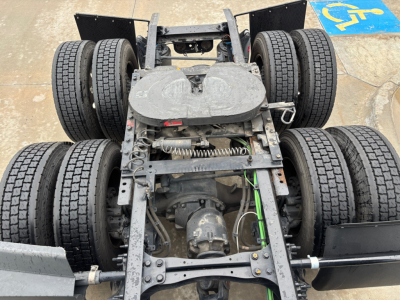 Conventional sleeper truck chassis showing rear axles and drivetrain with twin dual rear tandems and suspension components.
