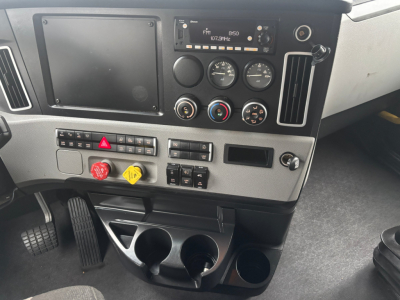 Dashboard of Freightliner PT126064ST showing radio, gauges, climate controls, switches, and cup holders.
