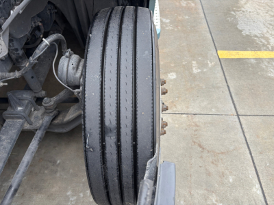 Conventional sleeper truck front wheel with multiple tread grooves and wheel hub bolts visible, part of Freightliner PT126064ST chassis.