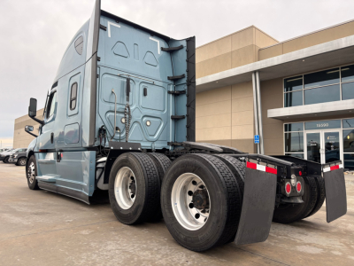 Freightliner PT126064ST truck rear angle showing tandem axles and mud flaps with cab and sleeper behind.