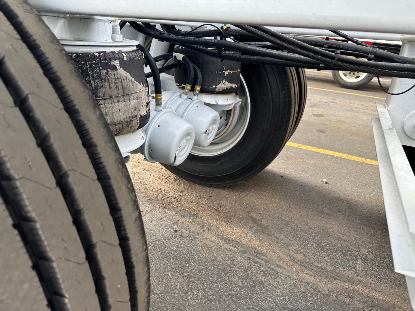 Bottom-dump trailer wheel hub area showing multiple air ride components and suspension lines.