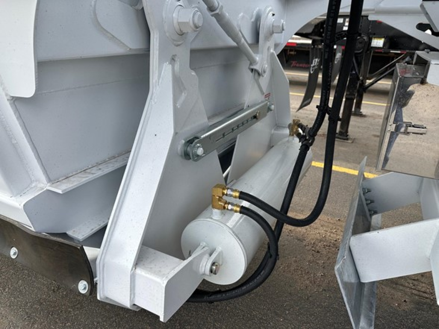 Trailers showing hydraulic line connections and a piston/actuator on a CPS bottom dump trailer, with hoses and fittings visible.