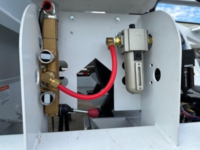 Bottom dump trailer internal valve manifold and hydraulic control lines with brass fittings, red cables, and electrical solenoid valve assembly.
