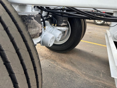 Bottom dump trailer wheel and hydraulic components showing dual axles and hydraulic cylinders and hoses