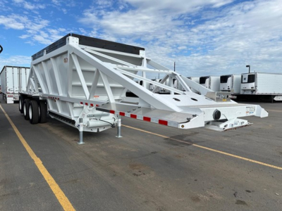 Bottom dump trailer showing white steel frame with triangular bracing on a multi-axle flatbed setup, long tongue, and landing gear in a parking lot.