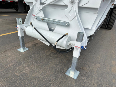 Bottom dump trailer landing gear and hydraulic hose assembly with steel legs and frame visible