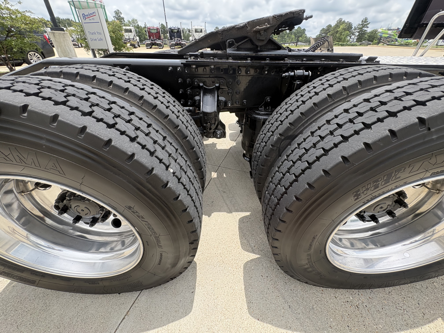 Dual rear axles of a 2024 Mack AN64T70 truck showing tires, wheels, and suspension components under the chassis.