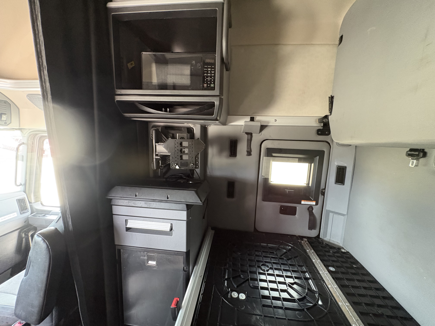 Truck cab interior with microwave, mounted storage, and control panel in sleeper area of a Mack AN64T70.
