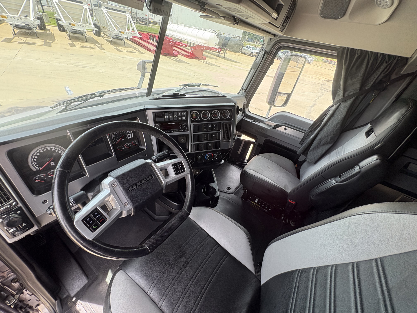 Mack AN64T70 truck cockpit interior showing steering wheel, dashboard gauges, center console, and driver seat.