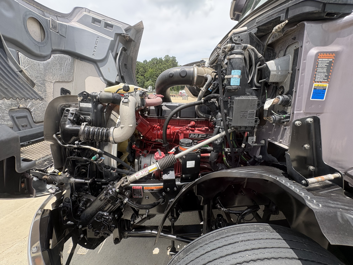 Mack AN64T70 truck engine bay showing red engine block and various hoses and components.