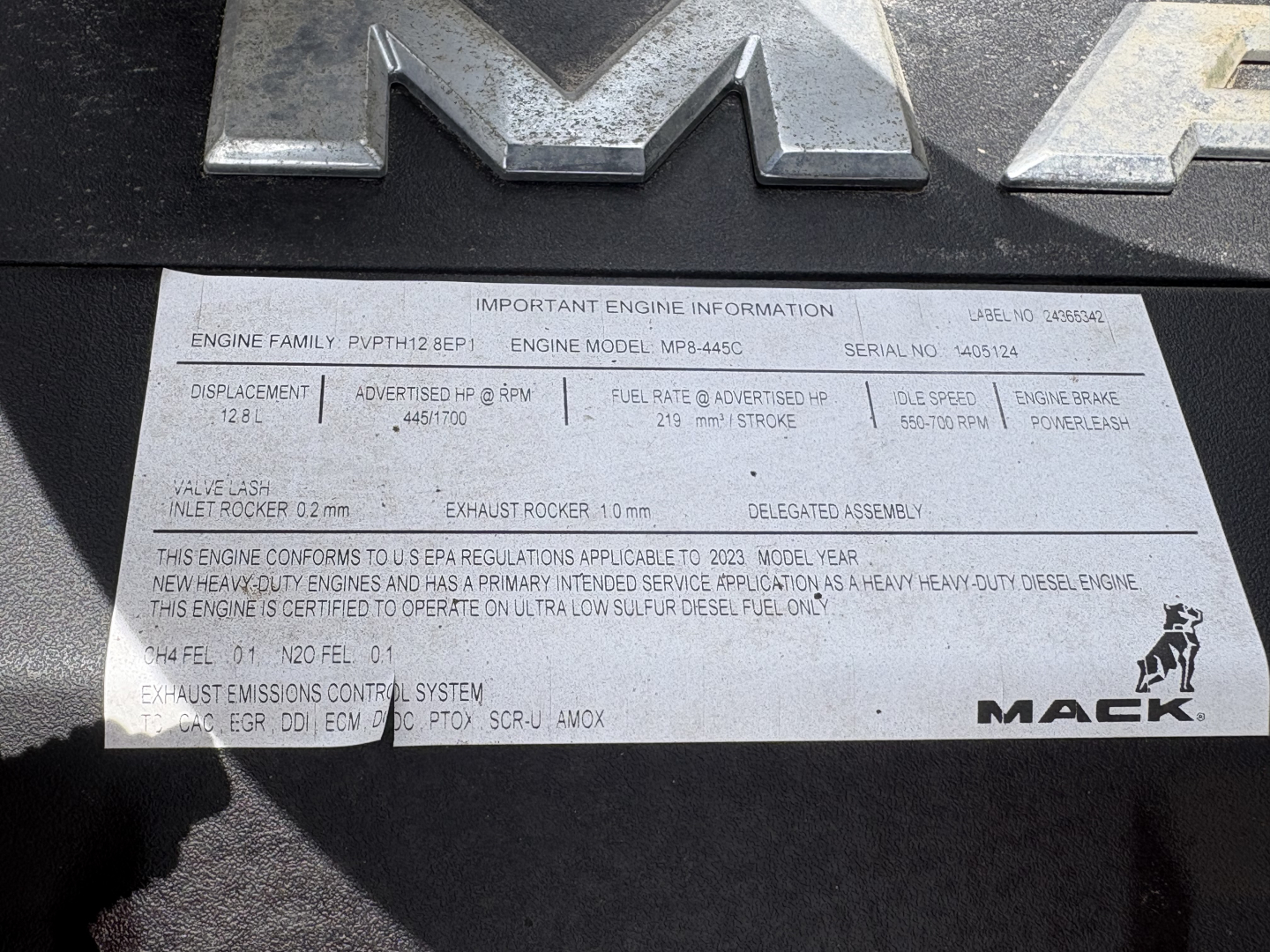Mack AN64T70 engine data plate with lines of text including engine family, model MP8-XS? and serial number, fuel system, exhaust, and other specs. Visible: IMPORTANT ENGINE INFORMATION, ENGINE FAMILY PPWT? BEP1, ENGINE MODEL MP8-4? Serial N