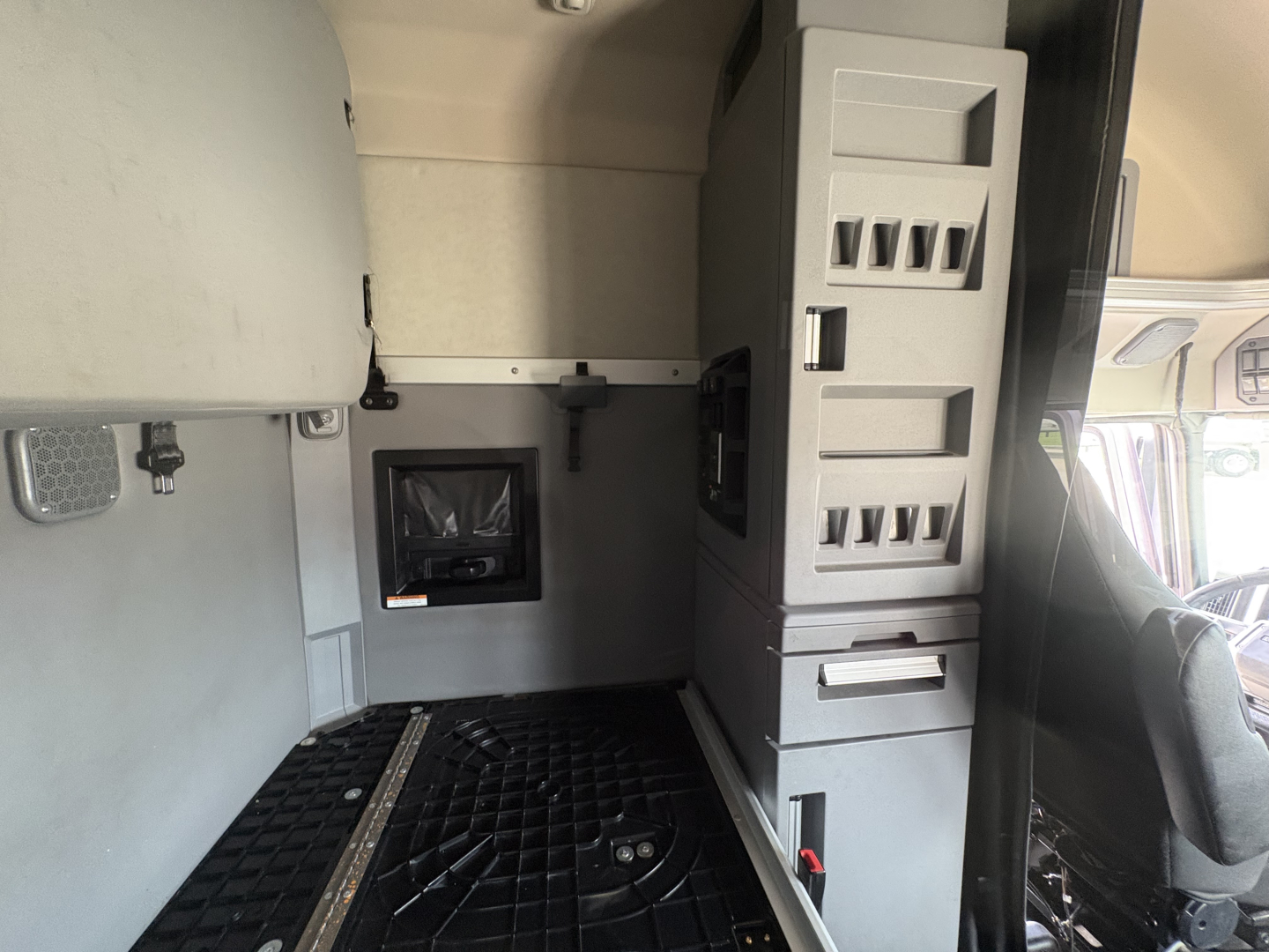 Conventional sleeper truck cab interior showing storage cabinets and dashboard area with electrical panel and windows