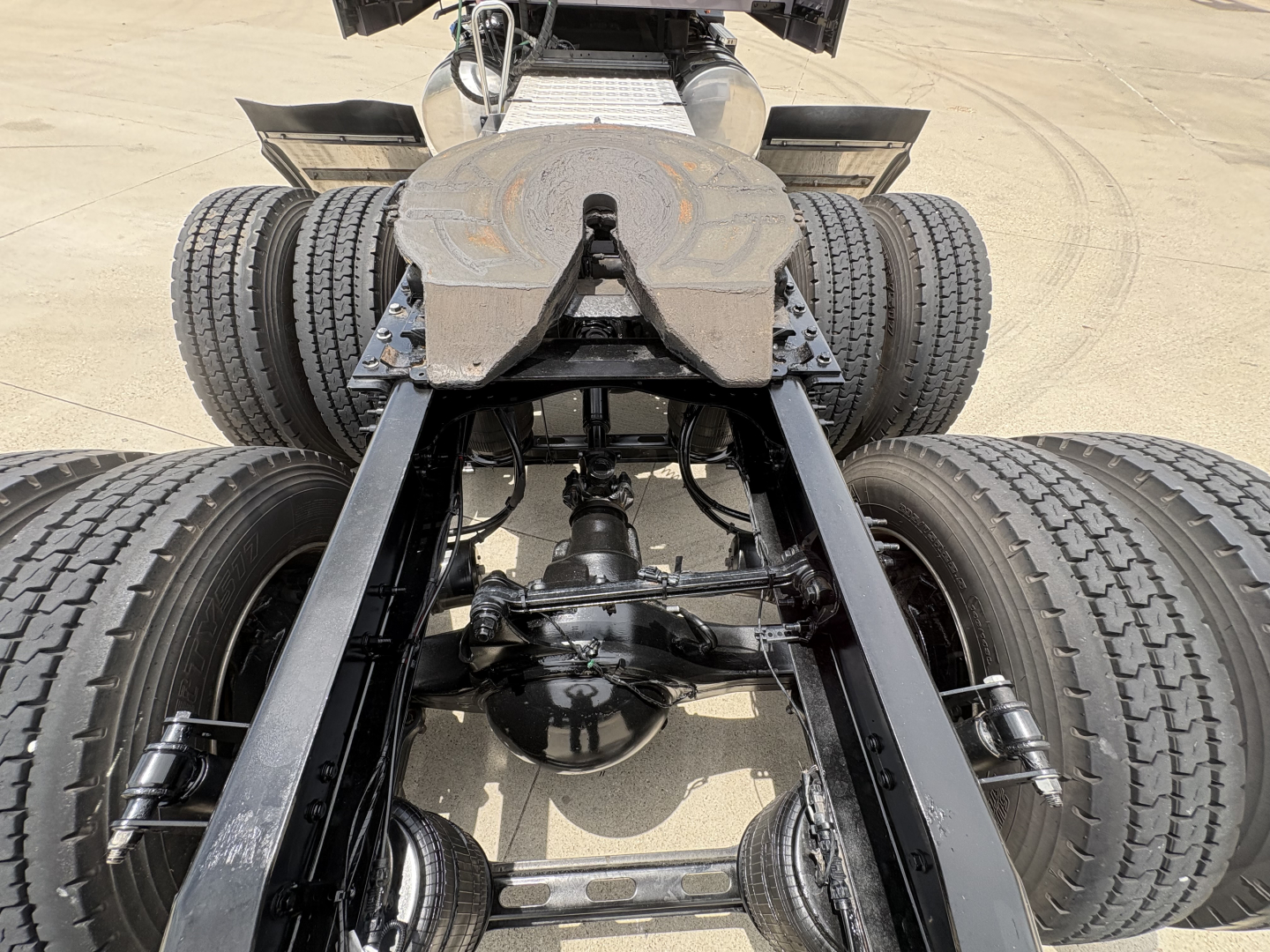 Rear view of Mack AN64T70 chassis showing dual rear axles and drivetrain components with fifth wheel visible and heavy-duty suspension.