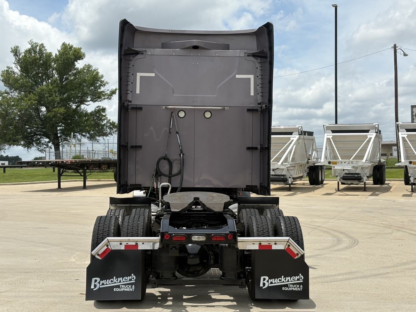 Mack AN64T70 tractor with rear view showing fifth wheel and dual rear axles, cab back door open, trailer hitch components visible.