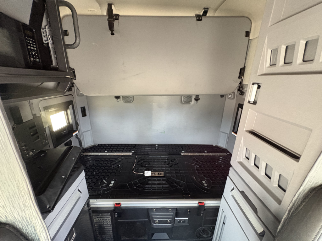 Truck cab interior showing sleeper area with storage cabinets and platform bed area