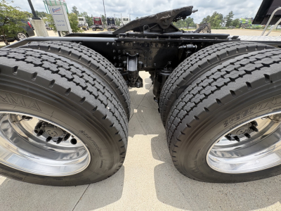 Dual rear axles of a 2024 Mack AN64T70 truck showing tires, wheels, and suspension components under the chassis.