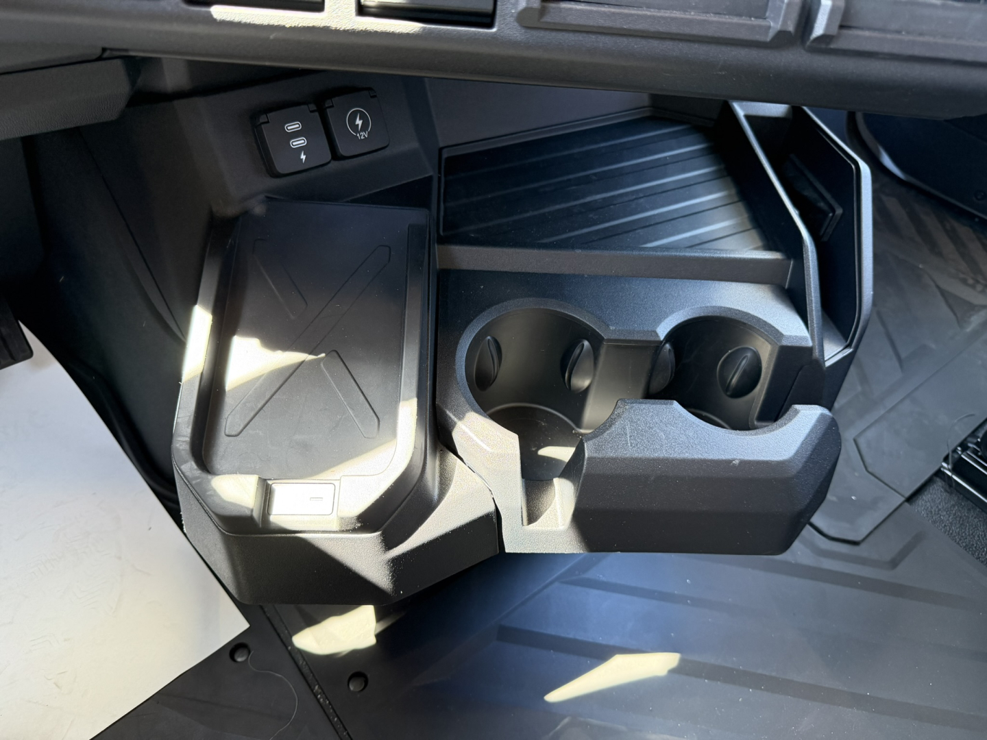 Cab interior storage and cup holders area of a 2027 Mack PR64T76H showing two cup holders and a small recessed storage bin under the dash.