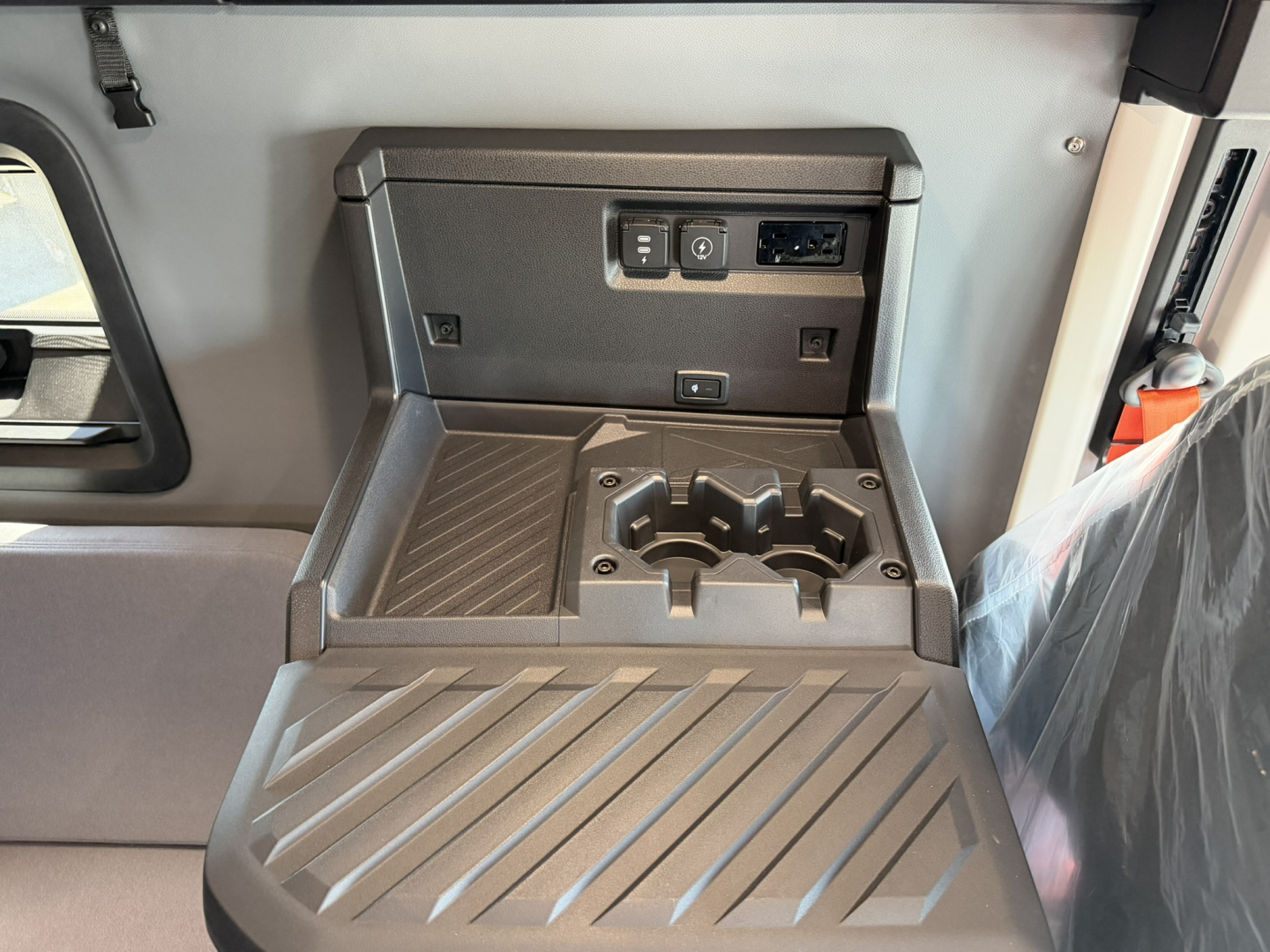 Interior center console of a Mack PR64T76H showing cup holders and storage, with power outlet and USB port panel.
