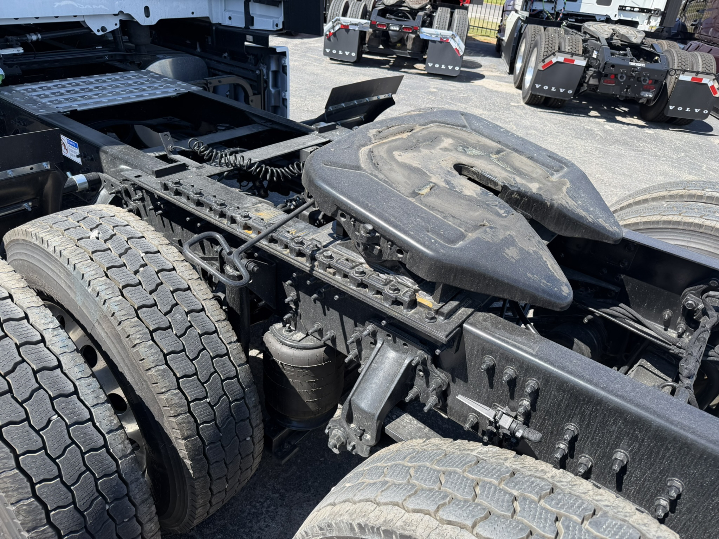 Chassis and cab area of a Mack PR64T76H truck showing dual rear axles, fuel tanks, and landing gear with fifth wheel area.