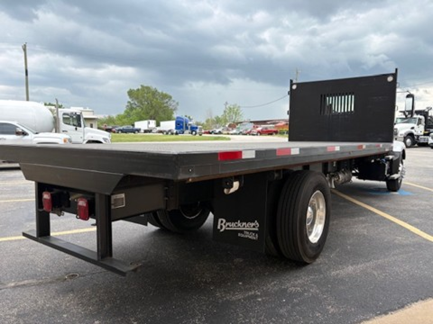 Flatbed truck chassis showing rear and side view with flat platform and dual rear tires, Mack MD6 (2025) likely on lot.