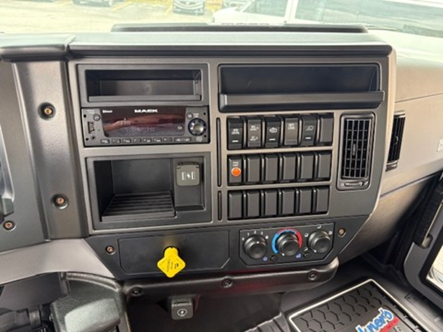 Dashboard of a 2025 Mack MD6 showing instrument cluster area with radio, controls, and climate dials.