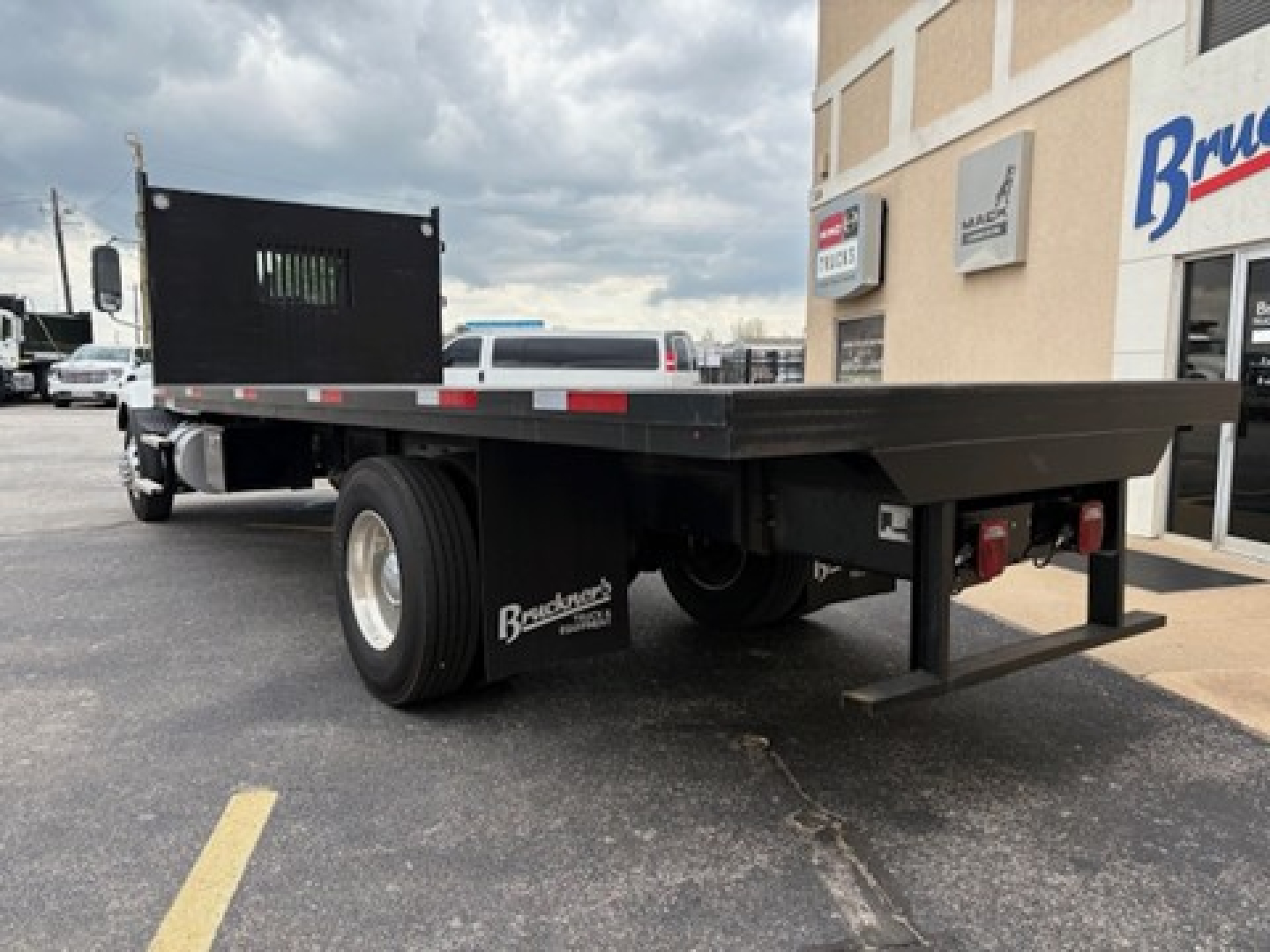 Mack MD6 flatbed truck rear view showing flatbed and dual rear wheels with mud flaps and Branden truck equipment branding.