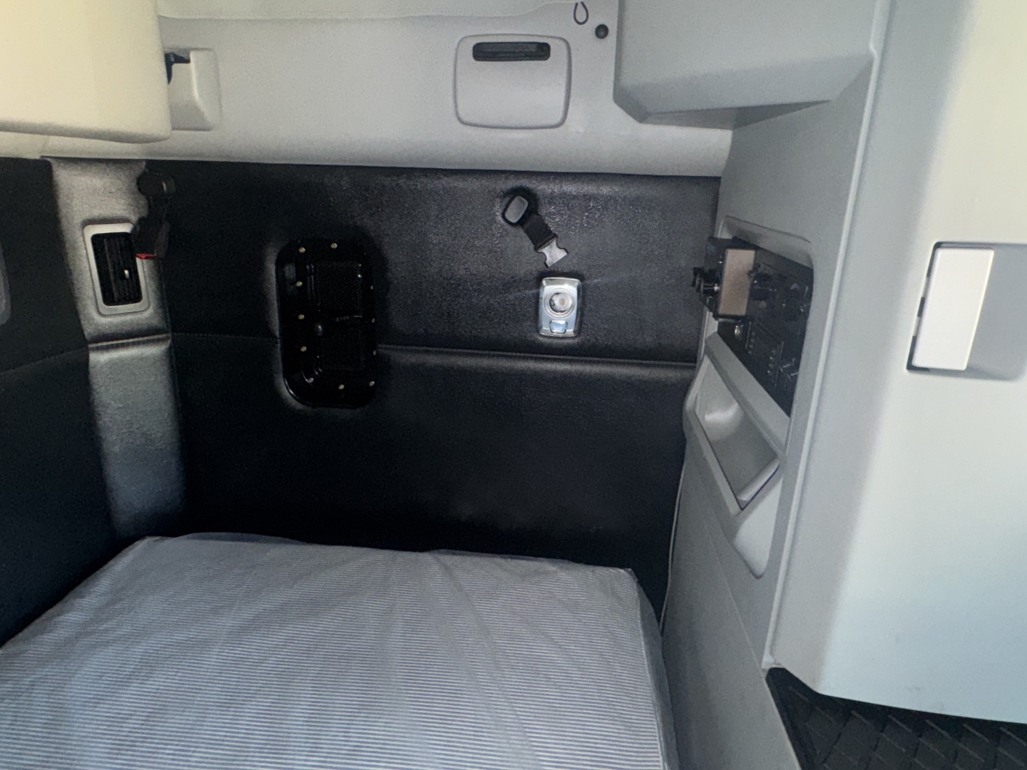 Kenworth T680 cab interior showing sleeper area with wall panel, hooks, and storage pocket.