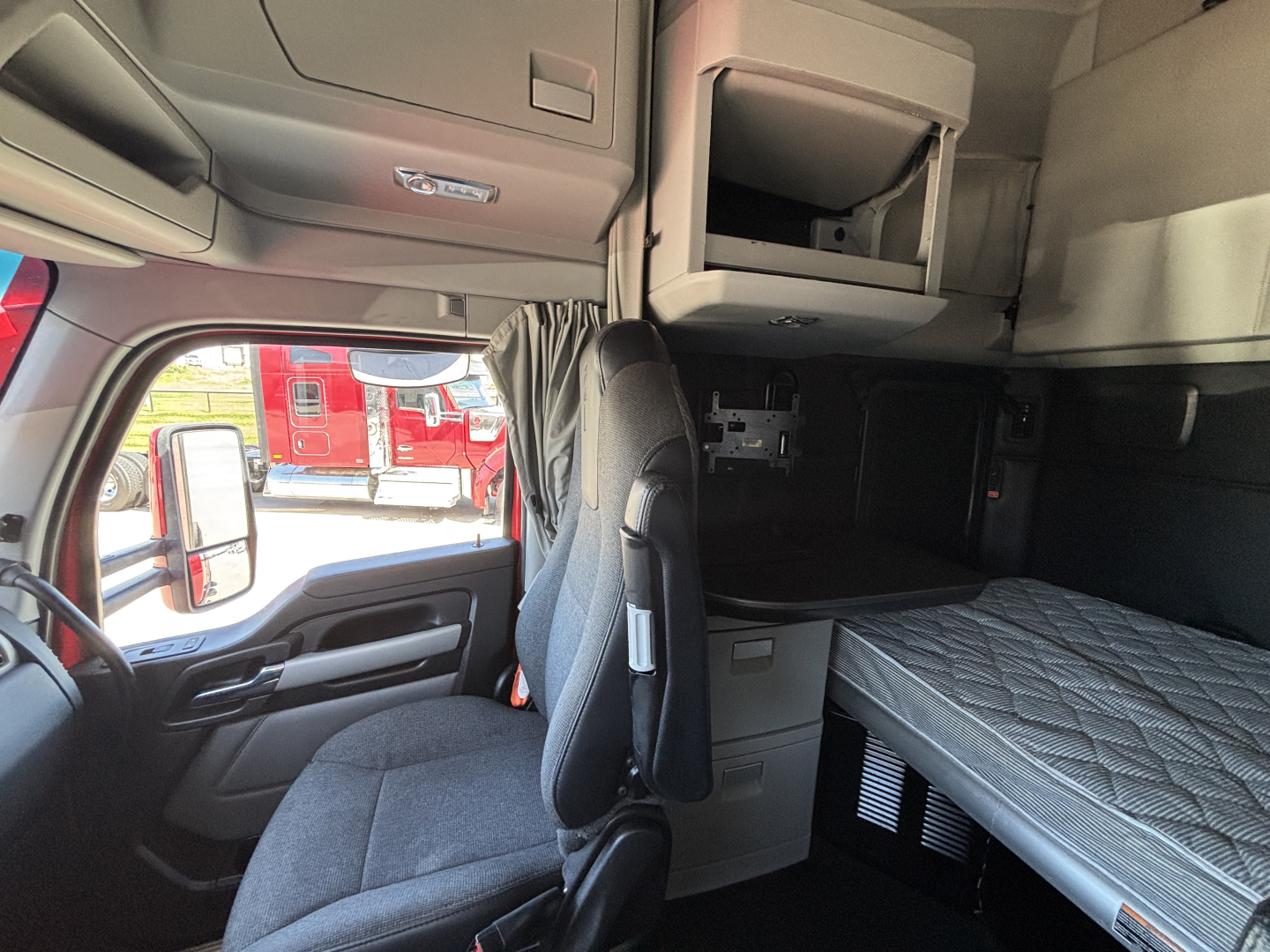 Truck cab interior with bunk bed, overhead storage, and passenger seat visible; no text legible besides interior features.