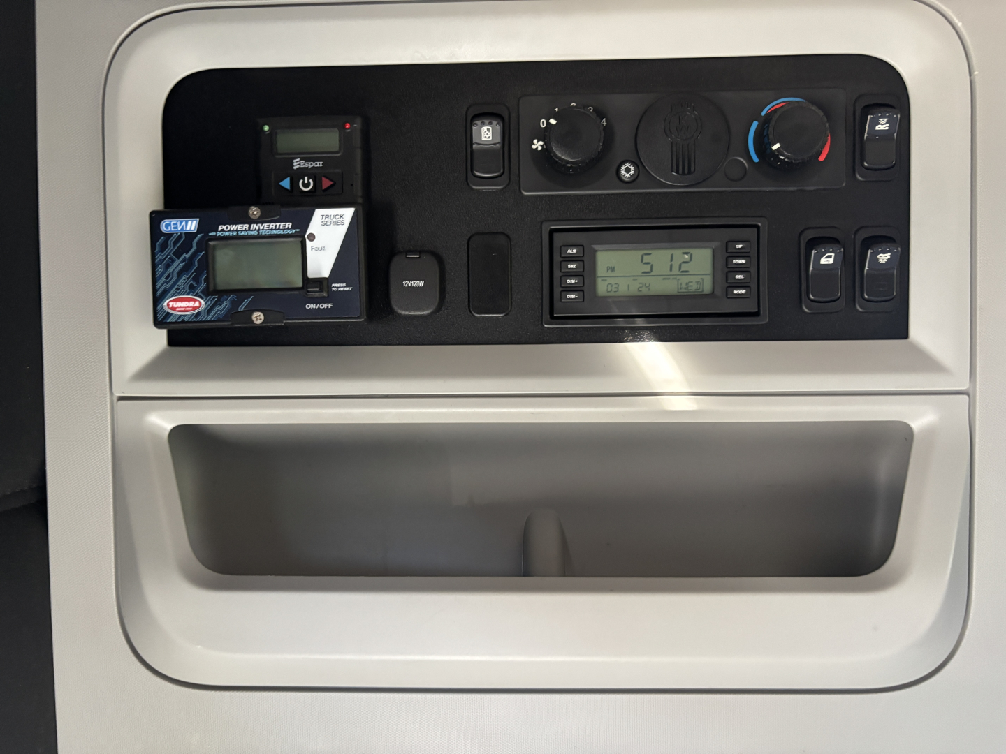 Dashboard panel of Kenworth T680 showing control dials, digital display, and a small device mount with a card, in-vehicle panel area.