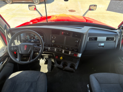 Interior of a 2023 Kenworth T680 cab showing steering wheel, dashboard, center console, and driver seat with visibility of gauges and controls.