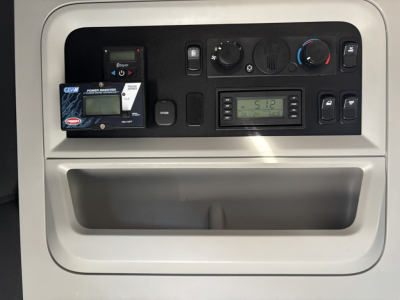 Dashboard panel of Kenworth T680 showing control dials, digital display, and a small device mount with a card, in-vehicle panel area.