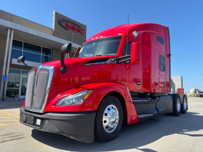 Red Kenworth T680 tractor cab, front left side view, daytime, in a dealership lot.