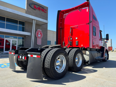 Kenworth T680 tractor 6x4 rear view showing red cab and dual rear axles with mud flaps.