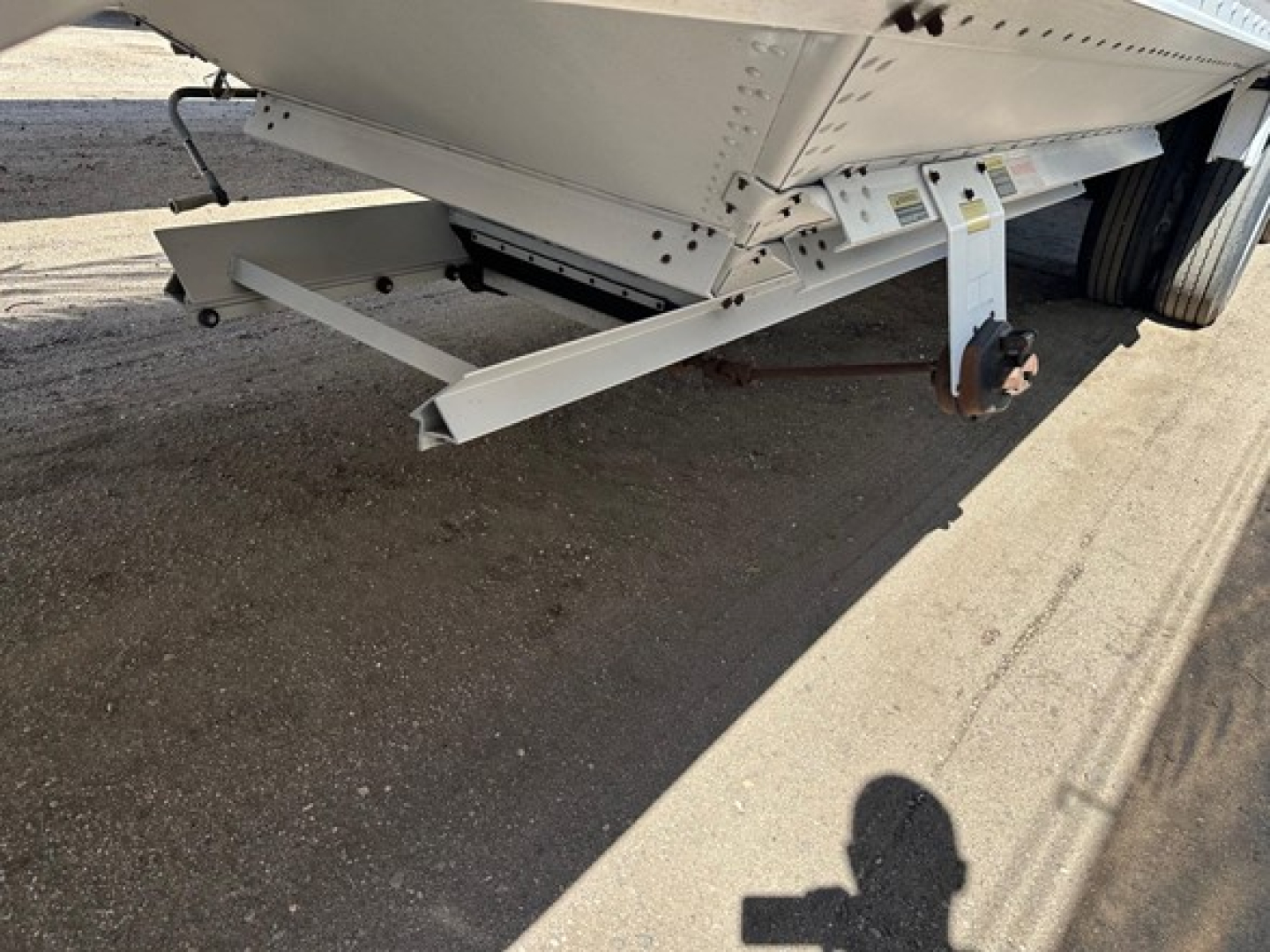 Trailer undercarriage with support legs and landing gear showing white painted steel, wheel and frame components visible.