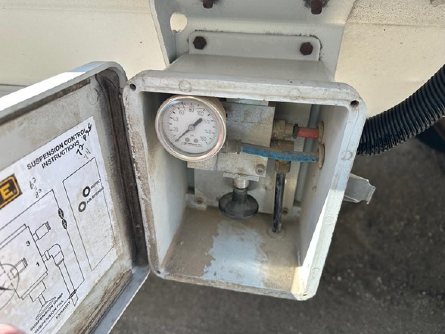 Hopper trailer control box with gauge and wiring showing pressure gauge and wiring, inside an open metal cover.
