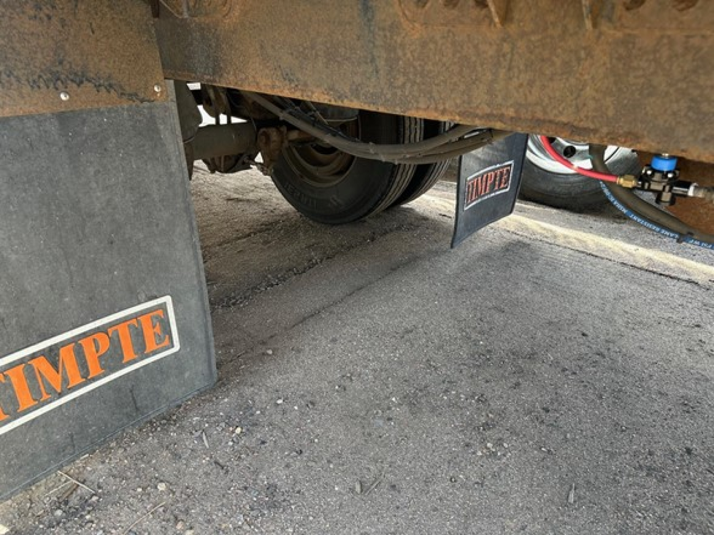Trailer underside showing Timpte logo mud flaps and wheel area of a hopper trailer.