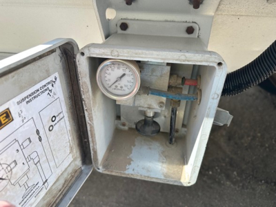 Hopper trailer control box with gauge and wiring showing pressure gauge and wiring, inside an open metal cover.