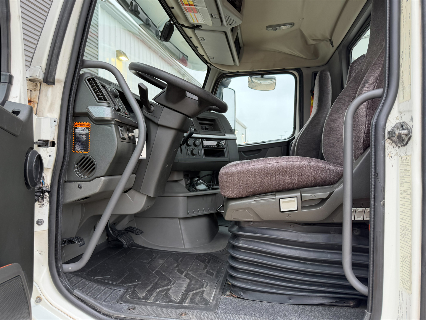 Volvo VNL-300 truck interior showing steering wheel, driver's seat, and dashboard with controls.