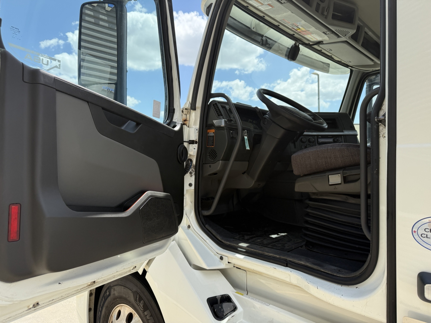  Volvo VNL300 cab interior showing driver seat and steering wheel with open door, dashboard, and steps visible.