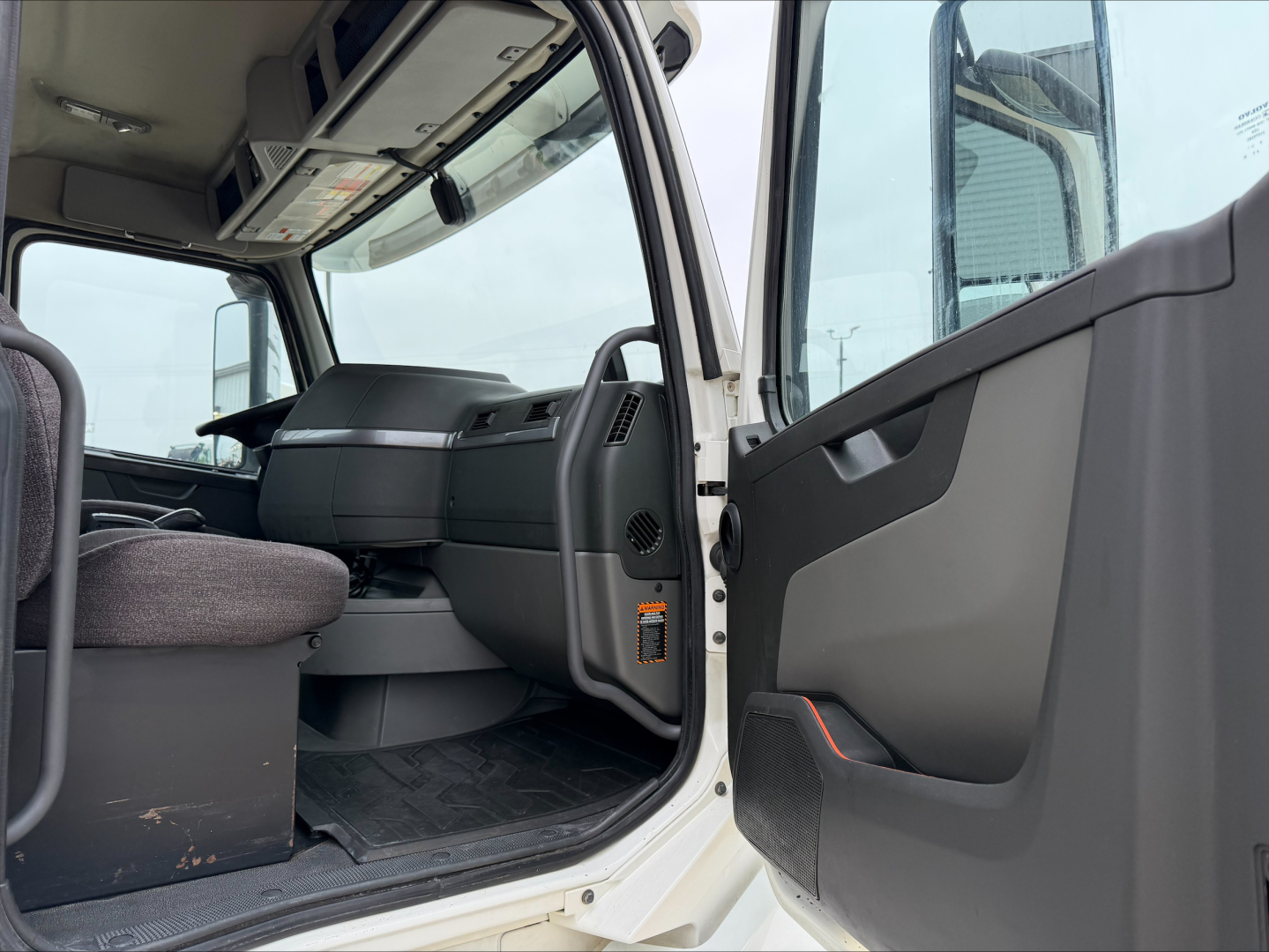 Interior of a 2019 Volvo VNL300 daycab truck cab view from passenger side door open showing steering wheel, dashboard, and entry step.